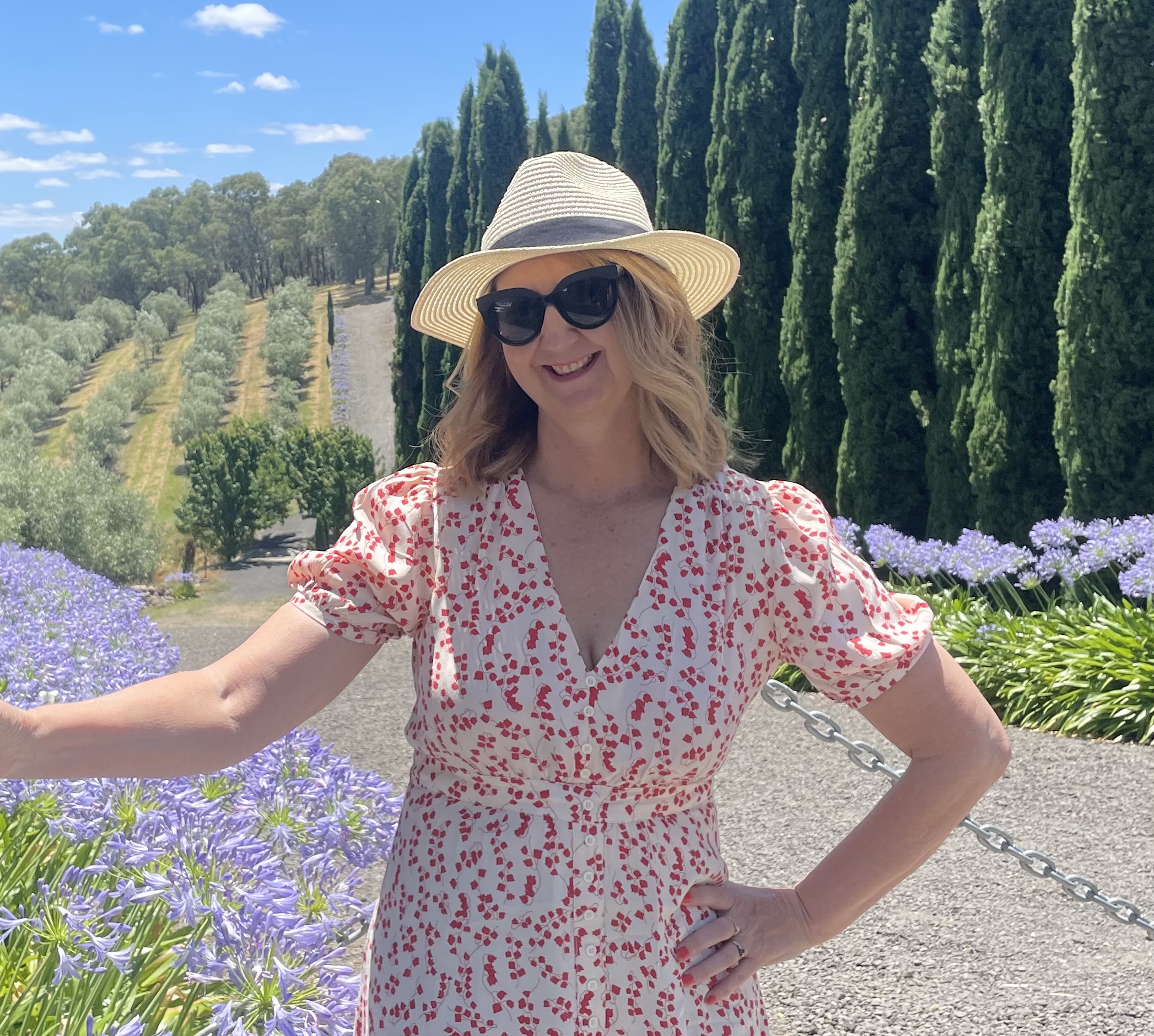 Woman in sun hat at garden with cypress trees